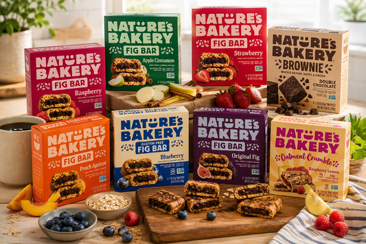 Nature’s Bakery lifestyle scene featuring assorted fig bars, oatmeal crumble bars, and brownie bars arranged on a rustic kitchen table with fresh fruit, oats, coffee, and wholesome snack ingredients in a bright natural setting.