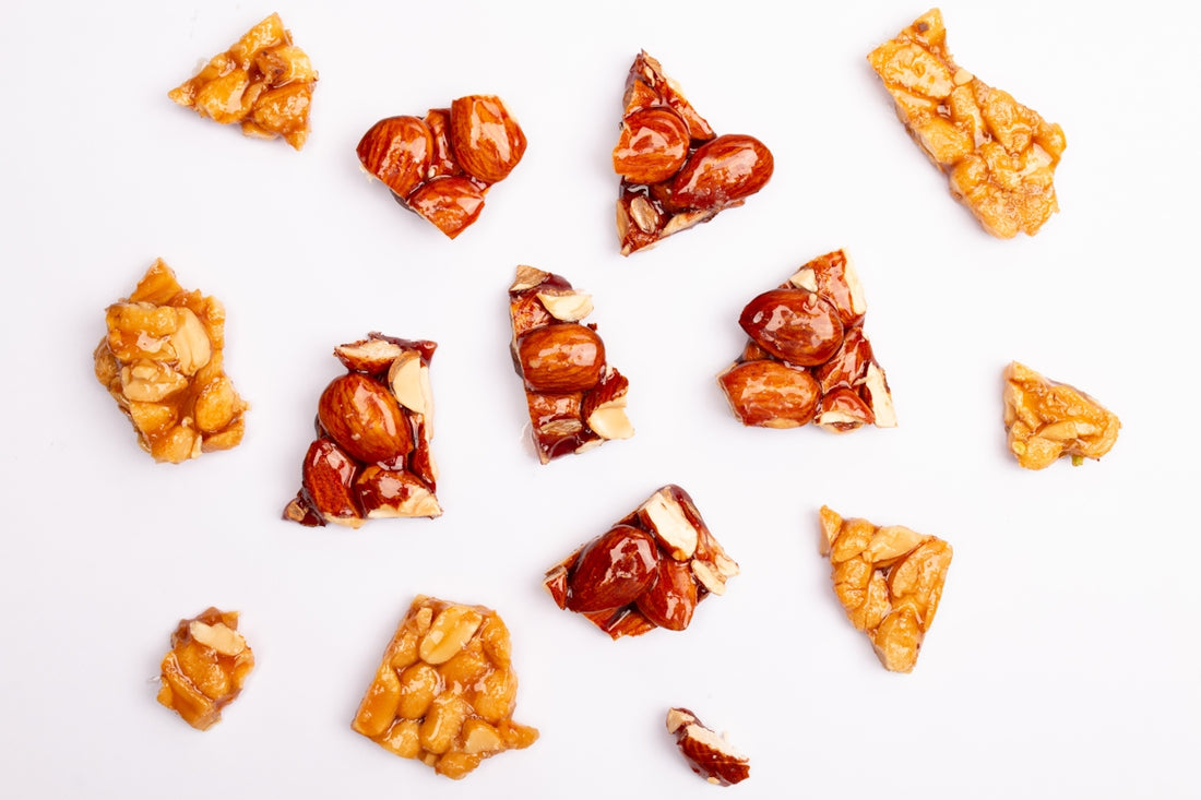 Assortment of peanut brittle pieces scattered on white background