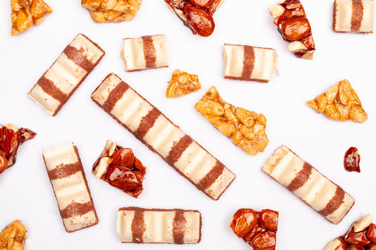 Assorted chocolate bars and brittle snacks arranged on white