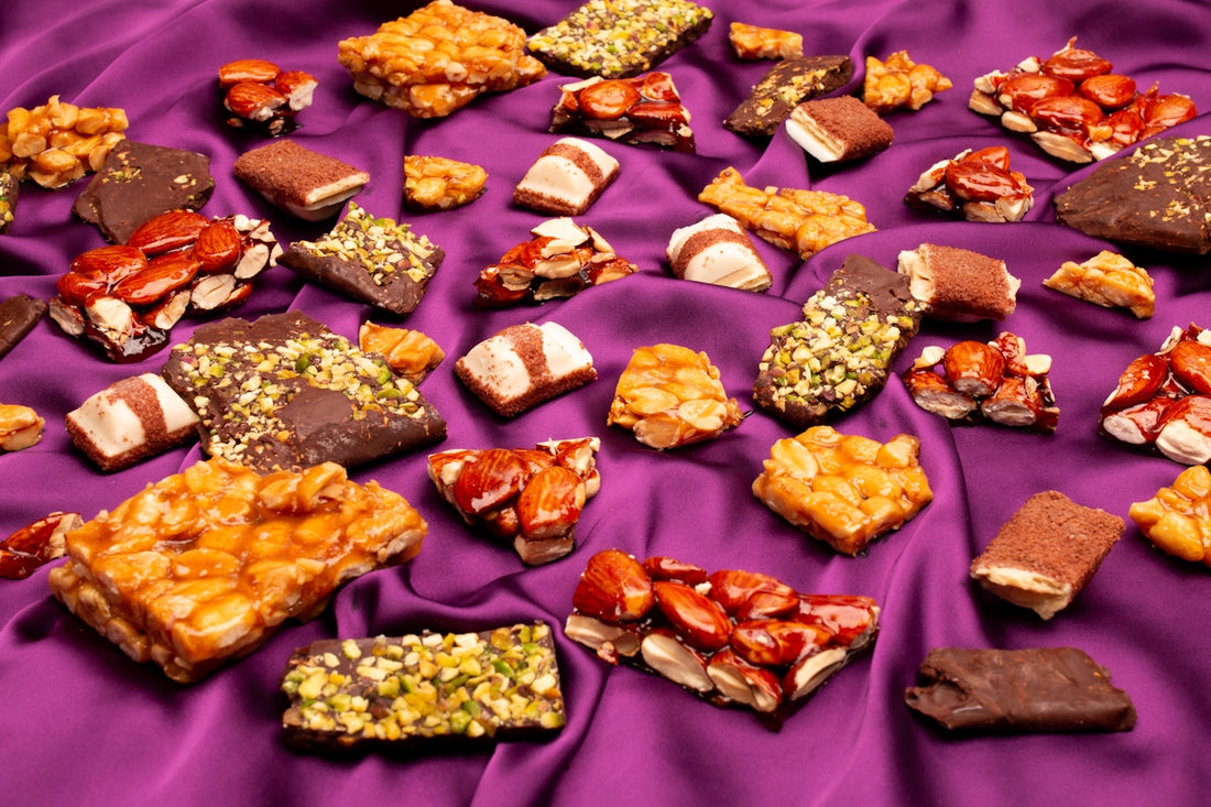 Assortment of chocolate candies and nuts on purple fabric.