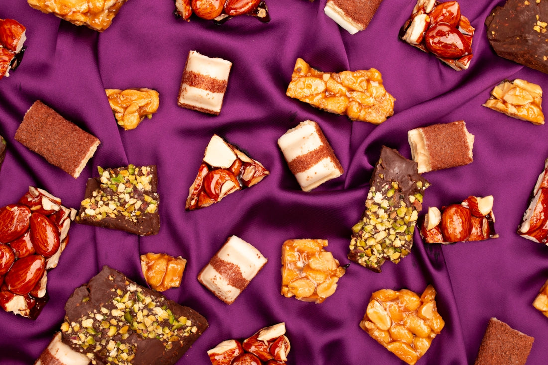 Assortment of chocolate bars and nut brittle on purple silk.