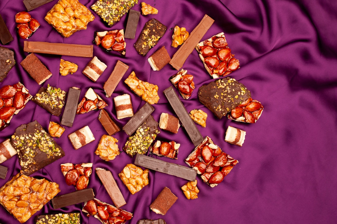 Assorted chocolate bars and candies scattered on purple fabric