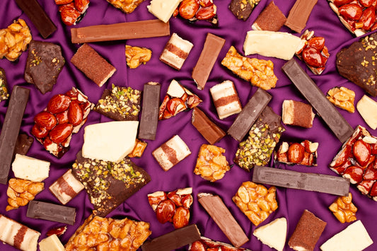 Assortment of chocolate bars and candies on purple fabric